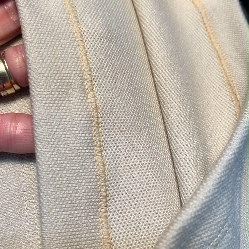 Close-up of neat topstitching along the edge of cream fabric
